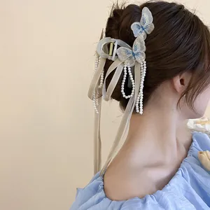 Dettaglio di un fermaglio per capelli a farfalla in acrilico con ricami, perle e nastri