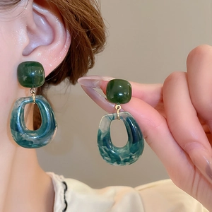 Detailed close-up of dark green and marble resin geometric earrings worn by a model