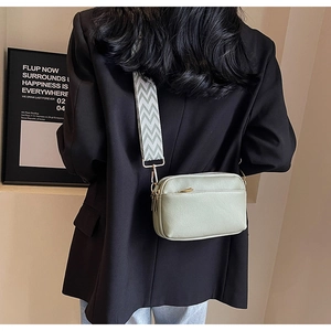 Detail of light green PU leather crossbody bag with ripple pattern wide shoulder strap