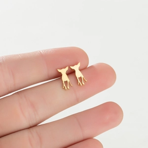 Close-up of minimalist golden puppy silhouette stud earrings held in hand