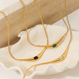 Golden snake chain necklaces with colorful natural stones on a white shell tray display