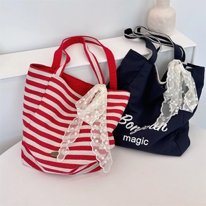 Detail of canvas tote bags with red stripes and navy fabric with lace bow accents