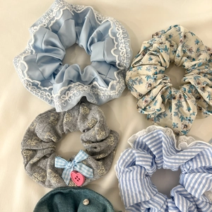 Detailed close-up of 5 lace scrunchies in assorted colors with bows and rhinestones