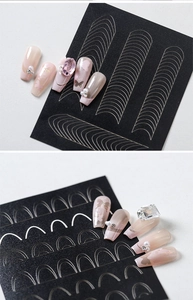 Close-up of French tip nail guides with gold accents and 3D butterfly jewelry nails
