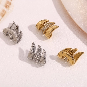 Macro shot of 18K gold and silver claw earrings with micro-inlaid zircons on white surface