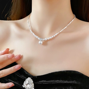 Detailed view of zircon and faux pearl necklace with silver pendant on model