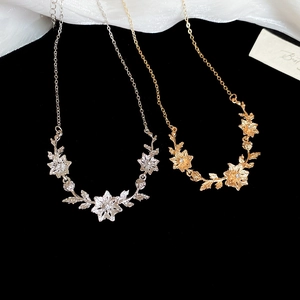 Close-up of gold and silver floral pendant necklaces with leaf design on black velvet