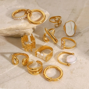 Collection of golden stainless steel rings with shell and zircon on natural stone