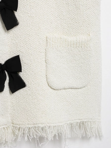 Detail aus weißem Tweed-Stoff mit schwarzer Schleife und elegantem Fransen-Saum-Dekor