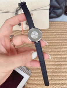 Close-up of elegant ladies' silver watch with grey dial and black leather strap by handbag