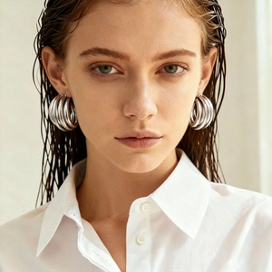 Close-up of model wearing silver multi-layered geometric hoop earrings in a minimalist style