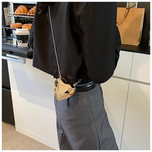 Chic gold heart-shaped mini metal crossbody bag with chain strap worn by a model