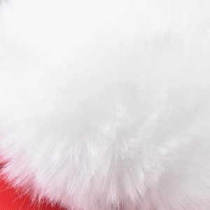Close-up of soft white faux fur pom-pom detail on a red winter Christmas baseball cap