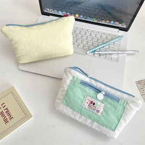 Multi-layer canvas pencil case with cute embroidery patches on a clean desktop