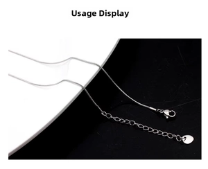 Close-up of silver snake chain necklace with lobster clasp, extender, and heart pendant