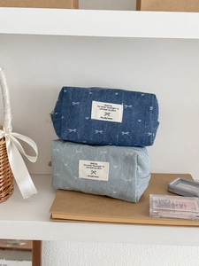 Close-up of denim bow organizer bags in light and dark blue with white woven labels