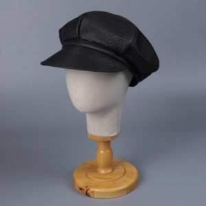 Classic black newsboy cap in textured woven fabric displayed on a mannequin head stand