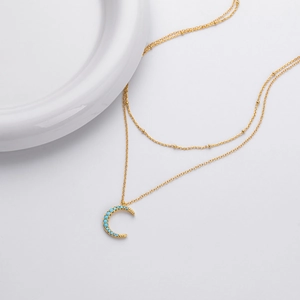 Detailed macro of golden double layer necklace with blue stone crescent moon pendant
