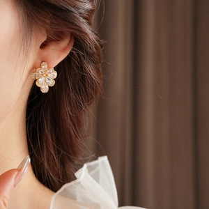 Side view of elegant floral zircon earrings worn by a model in warm lighting