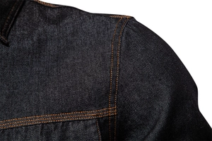 Détail des surpiqûres orange contrastées et de la texture sergée d'une chemise en denim