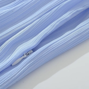 Gros plan sur un tissu plissé bleu clair avec détail de fermeture éclair blanche cachée