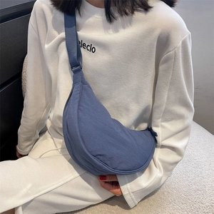 Blue crescent dumpling crossbody bag shown on model with adjustable strap for daily commute