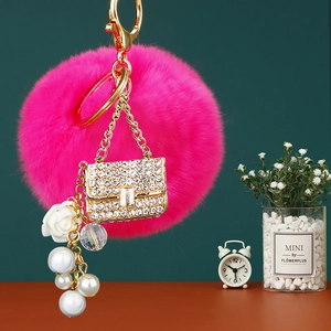 Macro shot of fuchsia pom-pom keychain with rhinestone handbag charm and white pearls