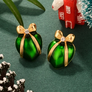 Macro view of heart-shaped green enamel gift box earrings with golden bow and crystals