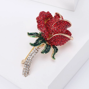 Dettaglio della spilla a rosa elegante con cristalli rossi e verdi su base bianca