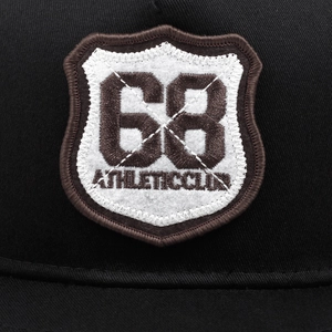 Close-up of the 68 Athletic Club shield embroidery on a black twill baseball cap