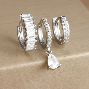 Macro detail of three silver earrings featuring teardrop and baguette-cut cubic zirconia
