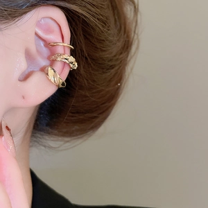 Détail d'un ensemble de trois bagues d'oreilles dorées aux textures lisses et martelées