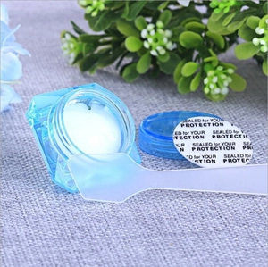 Detail of blue diamond-cut cosmetic jar with white cream and a translucent spatula