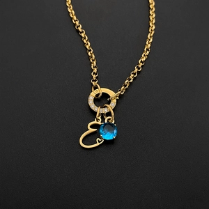 Detail view of gold titanium steel necklace with blue gem and letter E pendant.