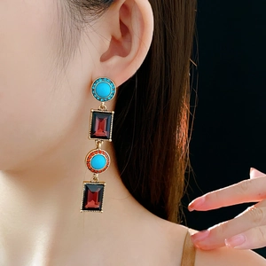 Close-up of vintage long fringe earrings with turquoise and ruby stones on black background