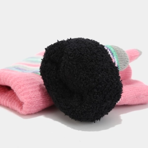 Detail of pink knitted winter hat with large black pompom and colorful stripe accents