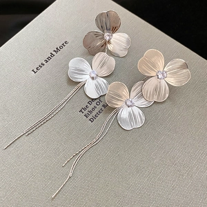 Macro shot of silver flower petal earrings with cubic zirconia and long metal tassel chain