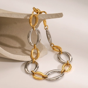 Modern two-tone gold and silver stainless steel chain bracelet on a minimalist display