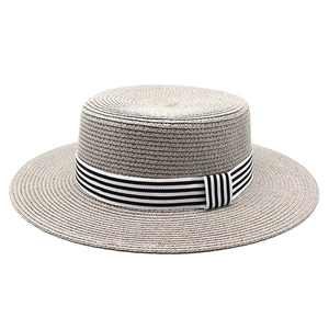 Detailed close-up of woven straw texture and striped ribbon on a flat boater hat