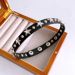 Close-up of black leather star rivet necklace with zircons on a wooden jewelry box