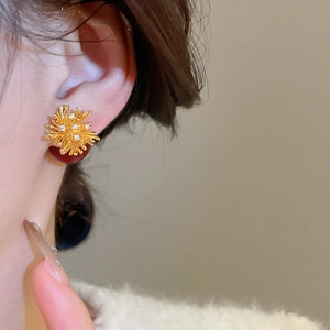 Detail of 18k gold plated sunburst earrings with zircon and deep red resin bead
