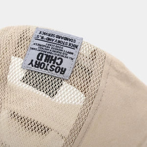 Close-up of beige mesh newsboy cap with grey rectangular logo patch detailing
