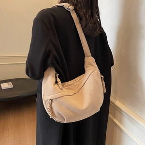 Minimalist beige corduroy crescent shoulder bag with bohemian woven tassel details