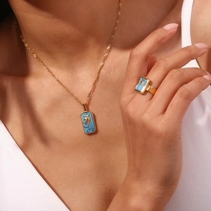 Detail view of 18K gold-plated necklace and ring with blue shell and palm tree charm