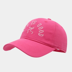 Detail of rose pink baseball cap featuring white GOD IS GOOD embroidery and bow design