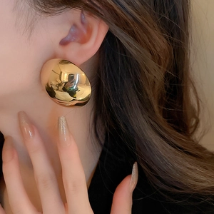 Close-up of a large gold striped semi-circle earring worn by a model in a profile view