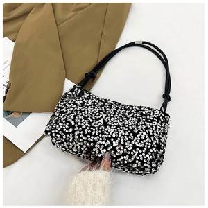 Close-up of sparkling silver sequins and knotted strap detail on a black shoulder bag