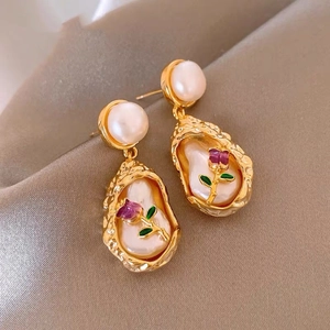 Detail of vintage French gold plated pearl earrings with pink rose embossing on satin