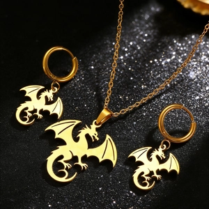 Gros plan sur collier dragon doré et boucles d'oreilles créoles sur fond noir texturé