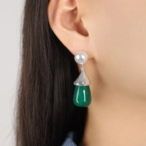 Deep green resin teardrop earrings with silver caps and white pearl details on a model